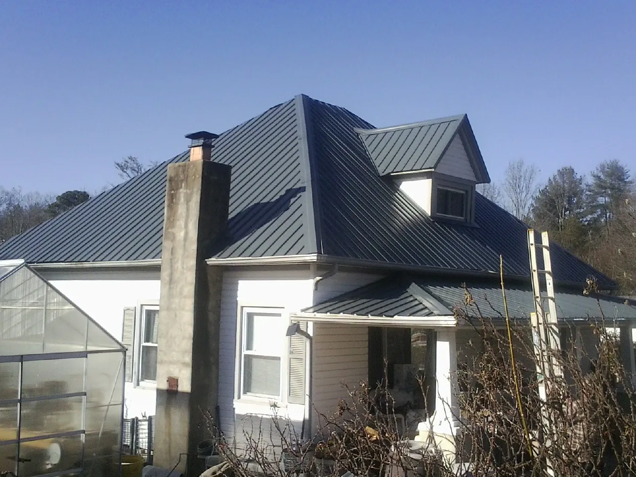 Dark blue standing seam metal roof on a white farmhouse with dormer — Slate & Tile Roof Repair by Roofing Brothers in Farmdale