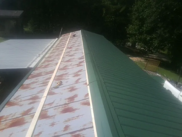 Old rusted panels beside newly installed green metal roofing — Wind Damage Roof Repair by Roofing Brothers in Farmdale