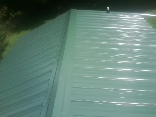 New green metal panels meeting at the ridge of a roof — Flat Roof Repair work by our crew in Farmdale