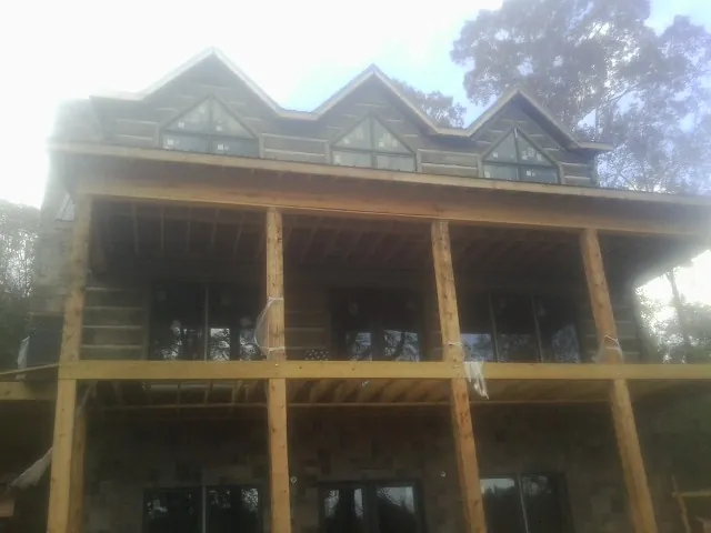 Dormers and porch framing on a large log home under construction — Roof Coating work by our crew in Farmdale