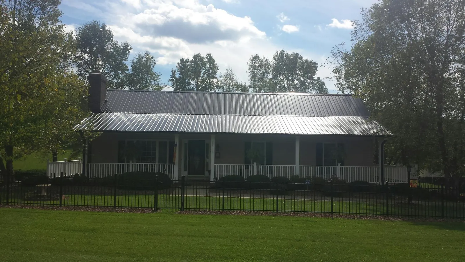 Gray metal roof on a brick ranch with a full width front porch — Gutter Guard Installation work by our crew in Farmdale