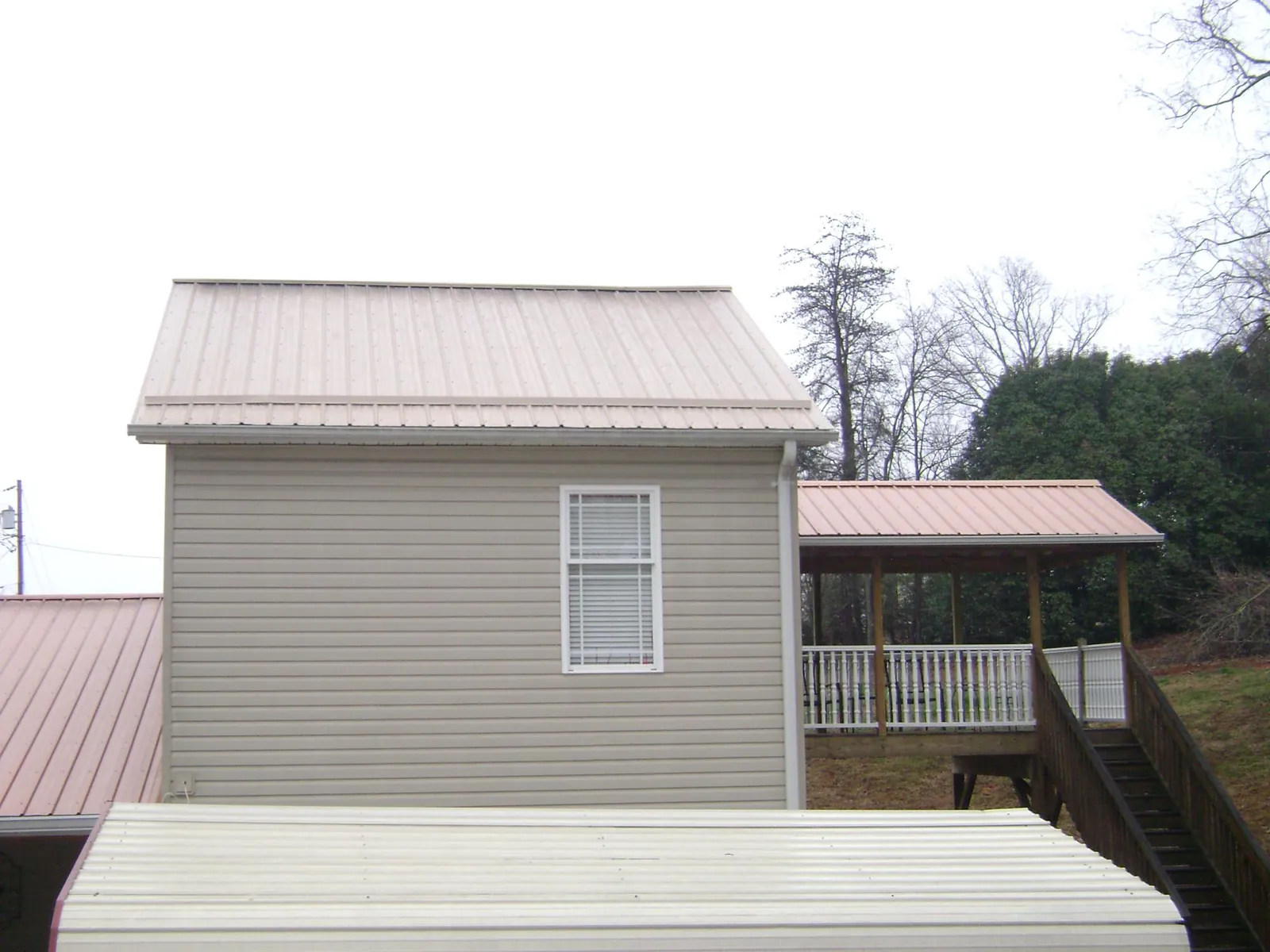 Tan metal roofs on a two story addition and attached porch, from a Roof Replacement job in Farmdale