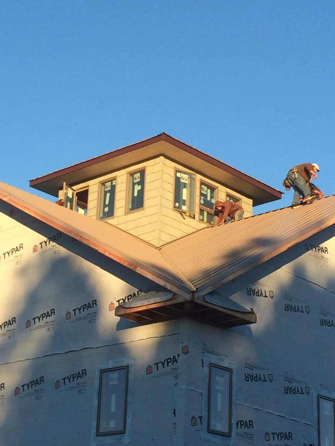 Roofers working around a rooftop cupola on a new metal roof at sunset — Roof Waterproofing in Farmdale by Roofing Brothers